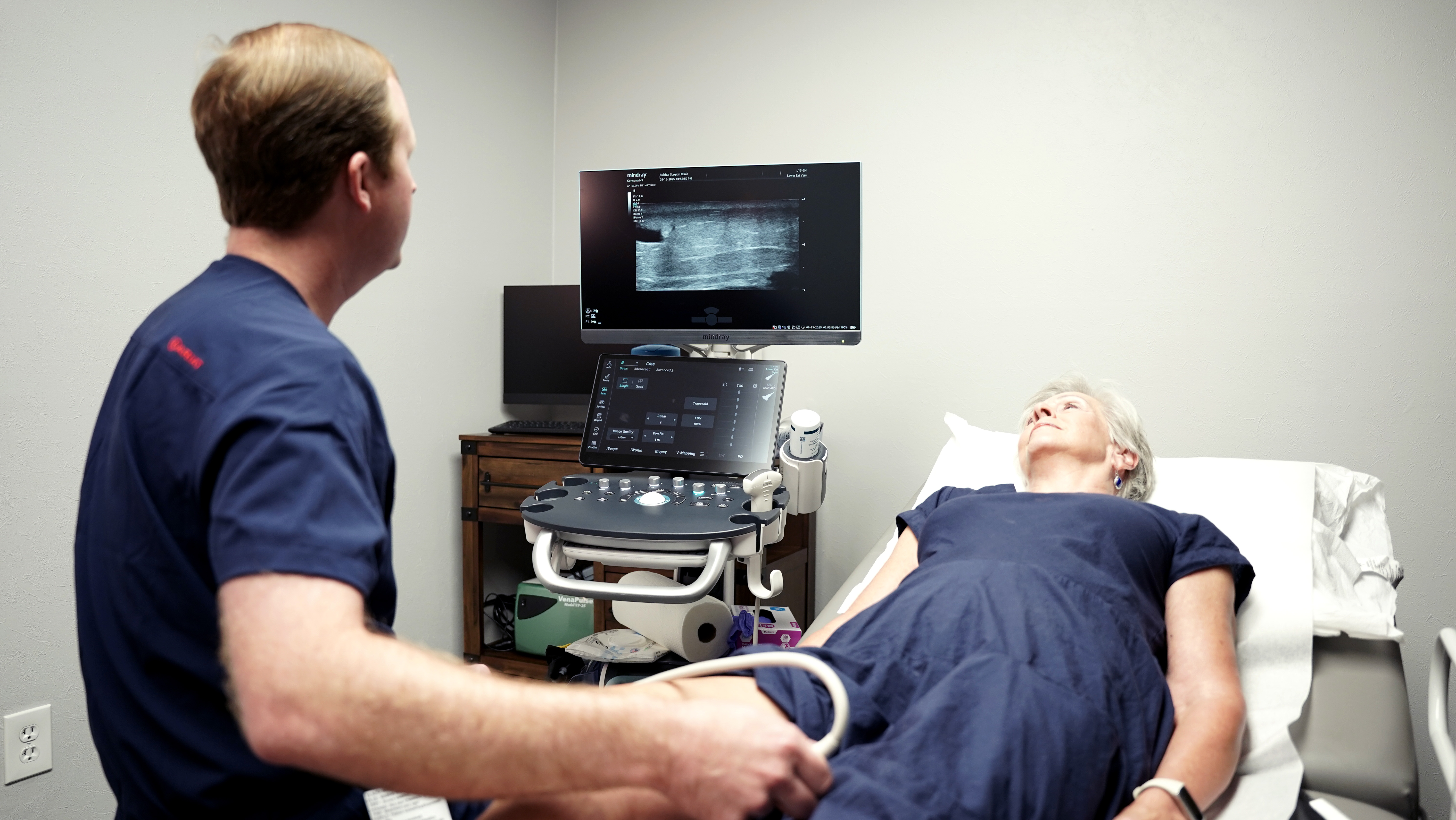 A surgeon performing a vein ultrasound on a patient's leg at the Lake Area Vein Center